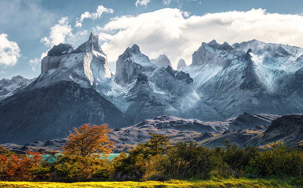 Massive rock peaks rising above a pristine lake in the Patagonian wilderness.